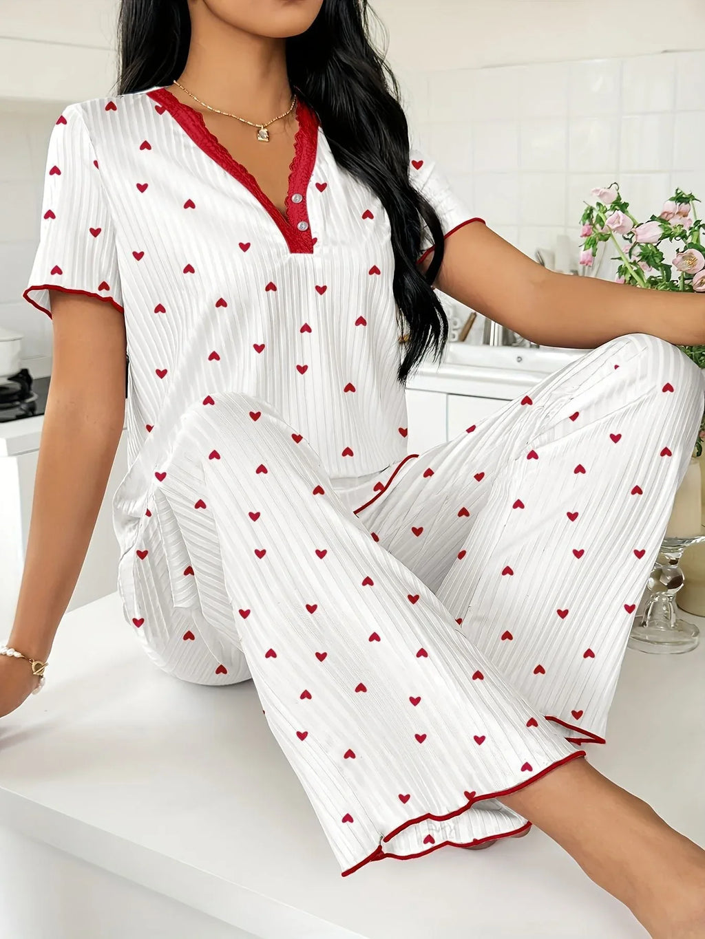 Woman wearing white and red heart print pajama set, sitting on a kitchen counter, close-up