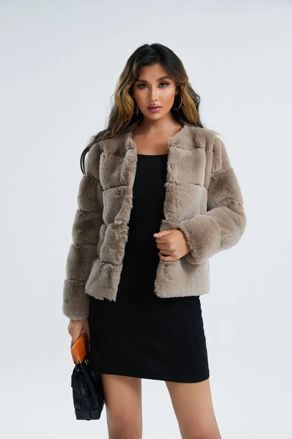 Woman wearing a pink faux fur cropped jacket with black shorts and a white crop top, side view.