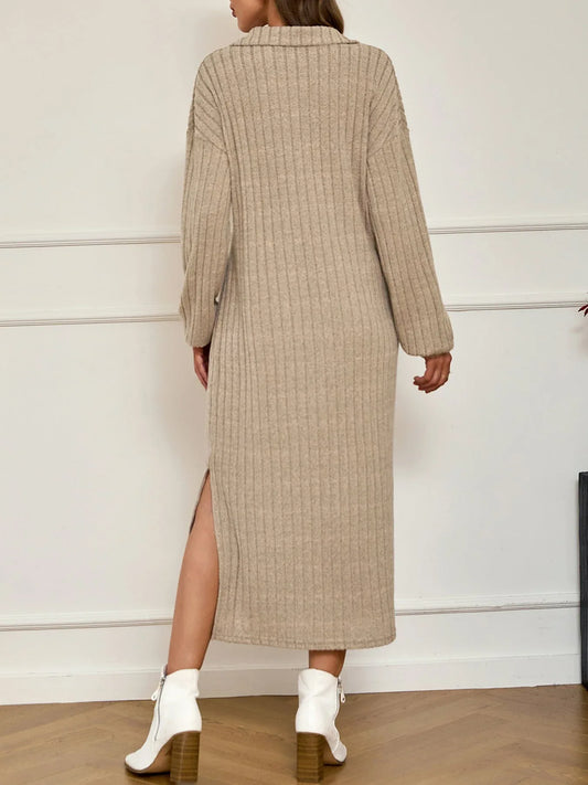 Back view of a woman wearing a beige ribbed knit midi dress with a collared V-neck and long sleeves, showcasing a side slit.