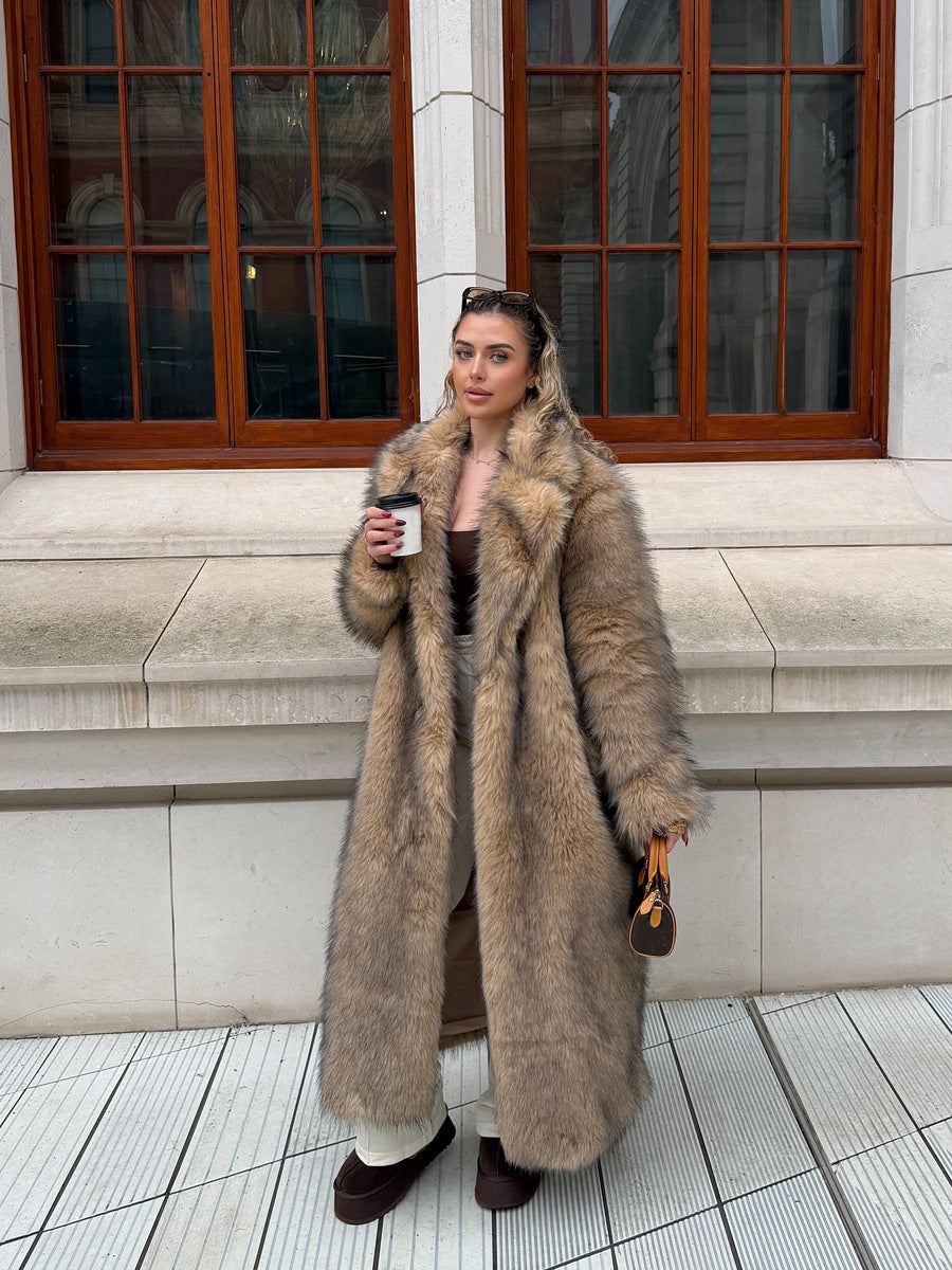 Woman wearing a long, beige faux fur coat with an oversized lapel, standing outdoors and holding a coffee cup.