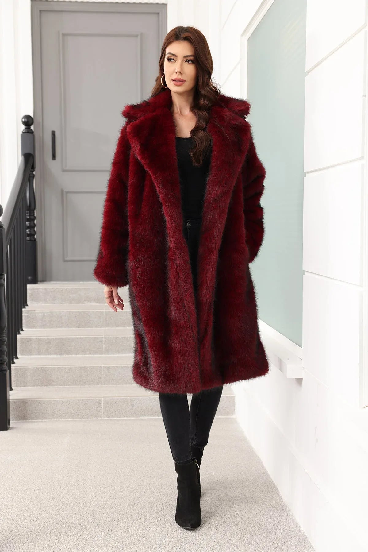 A woman wearing a long, burgundy faux fur coat over a black top and black pants, standing on stairs. Main image