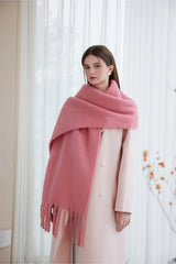 Woman wearing a pink oversized mohair blend scarf draped over a light pink coat.