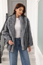 Woman in a grey faux fur jacket and white top, looking down.
