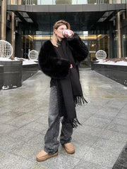 Woman wearing a black faux fur jacket and studded jeans, holding a coffee cup outdoors