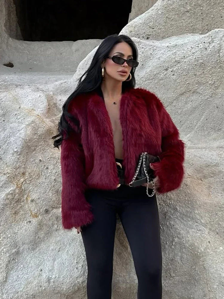 Woman wearing a burgundy faux fur cropped jacket with black leggings and sunglasses Main image