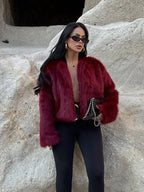 Woman wearing a burgundy faux fur cropped jacket with black leggings and sunglasses
