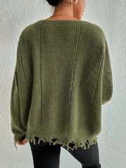 Back view of a woman wearing a green oversized distressed knit sweater with black pants