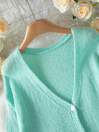 Close-up of the V-neckline and button detail on a light mint green mohair blend cardigan.
