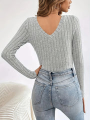 Back view of a woman wearing a grey ribbed long-sleeve V-neck top and jeans