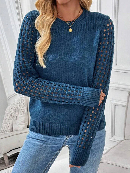 Woman wearing a blue knit sweater with cutout sleeves and blue jeans.