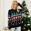 Woman in a festive Christmas sweater with various holiday motifs, posing in front of a Christmas tree.