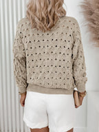 Back view of a woman wearing a beige open-knit V-neck cardigan with gold buttons and white shorts.