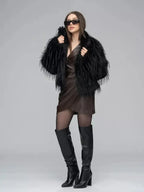 Woman wearing a black faux fur jacket over a brown wrap dress, black sheer tights, and black knee-high boots.