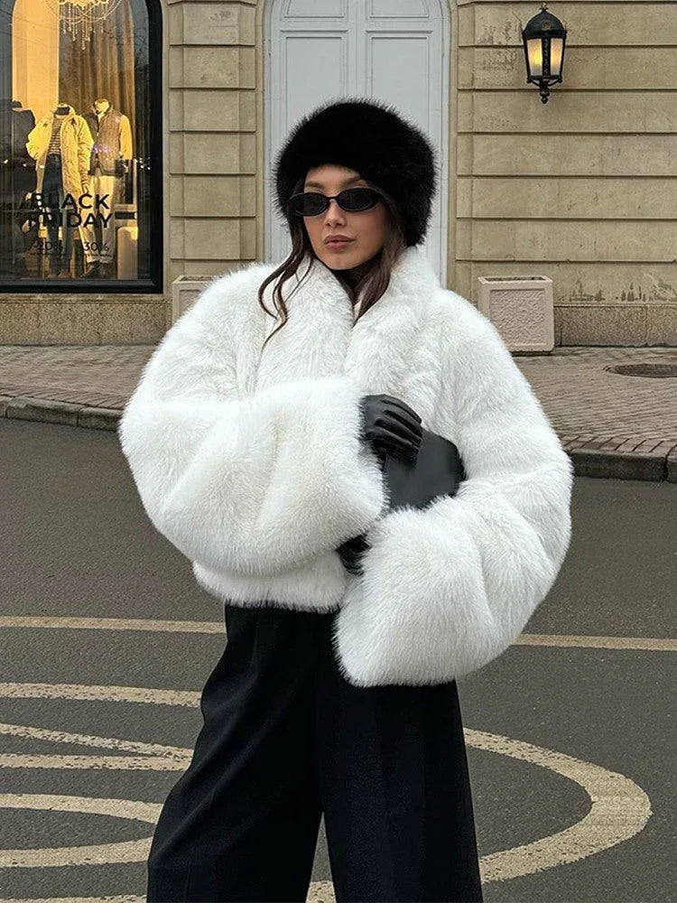 woman wearing a white faux fur cropped jacket with black pants and a black hat Main image