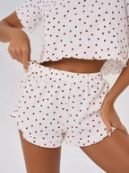 Close-up of the waistband and hem of white shorts with a red heart print and ruffled trim.