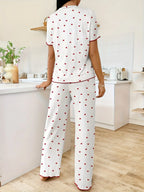 Woman wearing white and red heart print pajama set, standing with back to camera in a kitchen