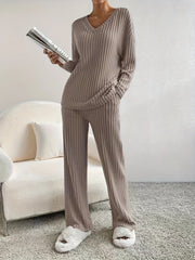 Woman standing in a beige ribbed loungewear set holding a magazine