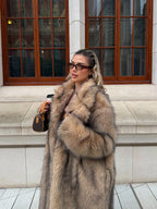 Close-up of a woman showcasing a luxurious faux fur coat with rich texture and a flowing silhouette.