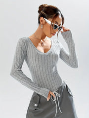 Woman adjusting her white sunglasses while wearing a grey ribbed long-sleeve bodysuit and grey cargo pants.