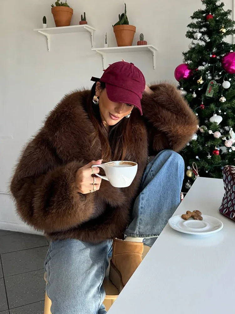 woman wearing a brown faux fur coat with jeans and a baseball cap, holding a coffee cup