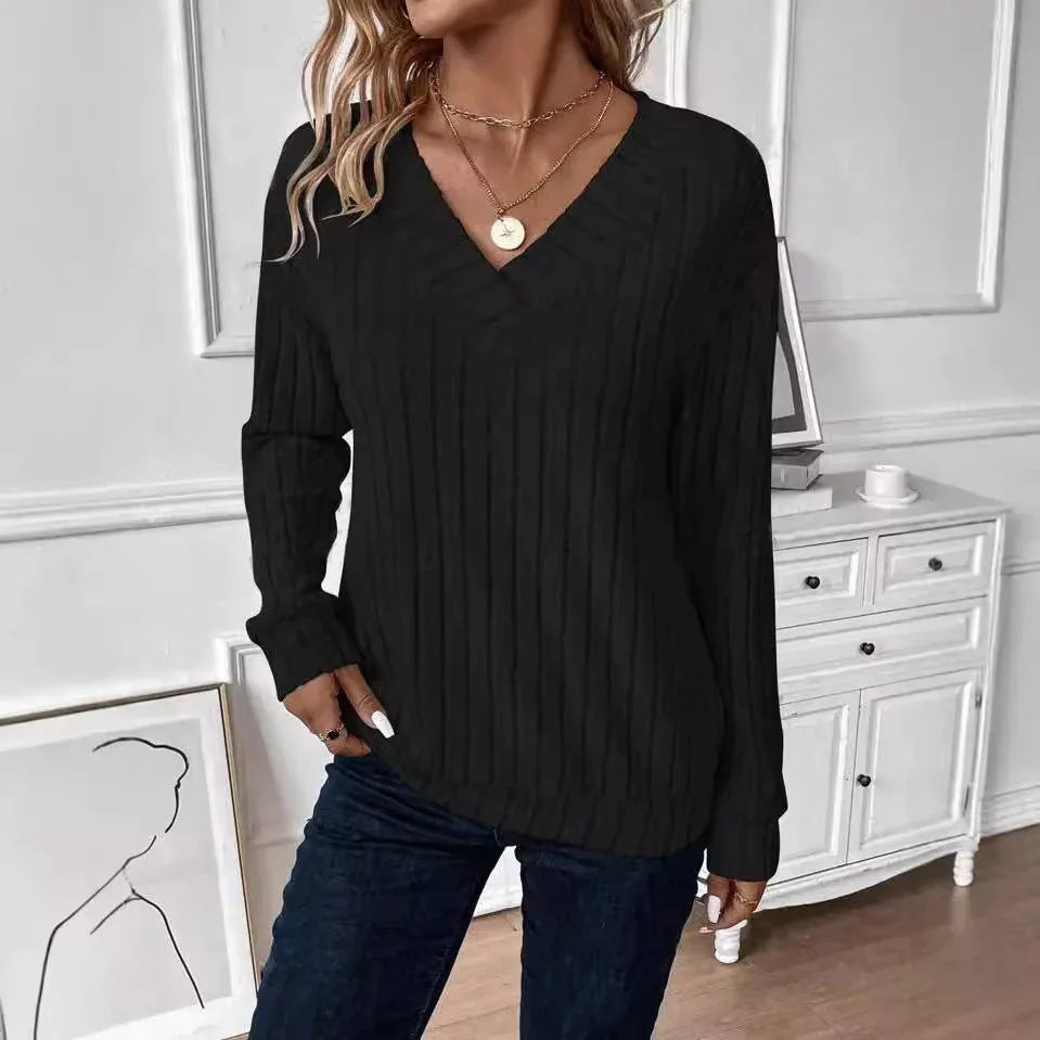 Front view of a woman wearing a black ribbed V-neck long-sleeve sweater, accessorized with gold necklaces.