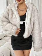 Close-up of a woman wearing a white faux fur cropped jacket and black dress.