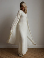 Woman wearing a long white ribbed knit dress with a matching flowing cardigan.