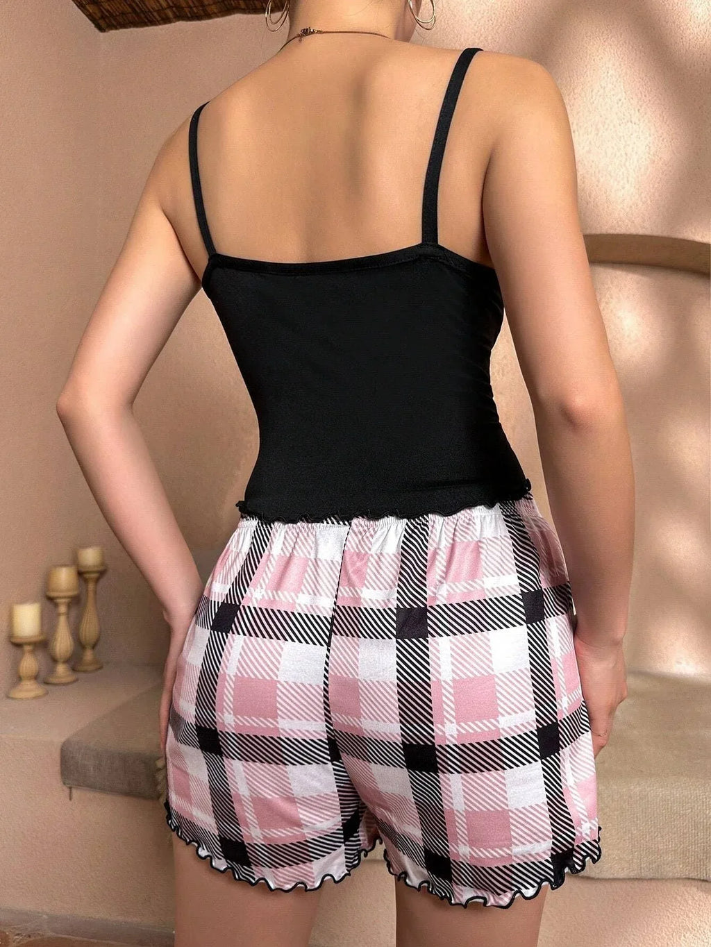 Back view of a person wearing a black camisole and pink plaid shorts.