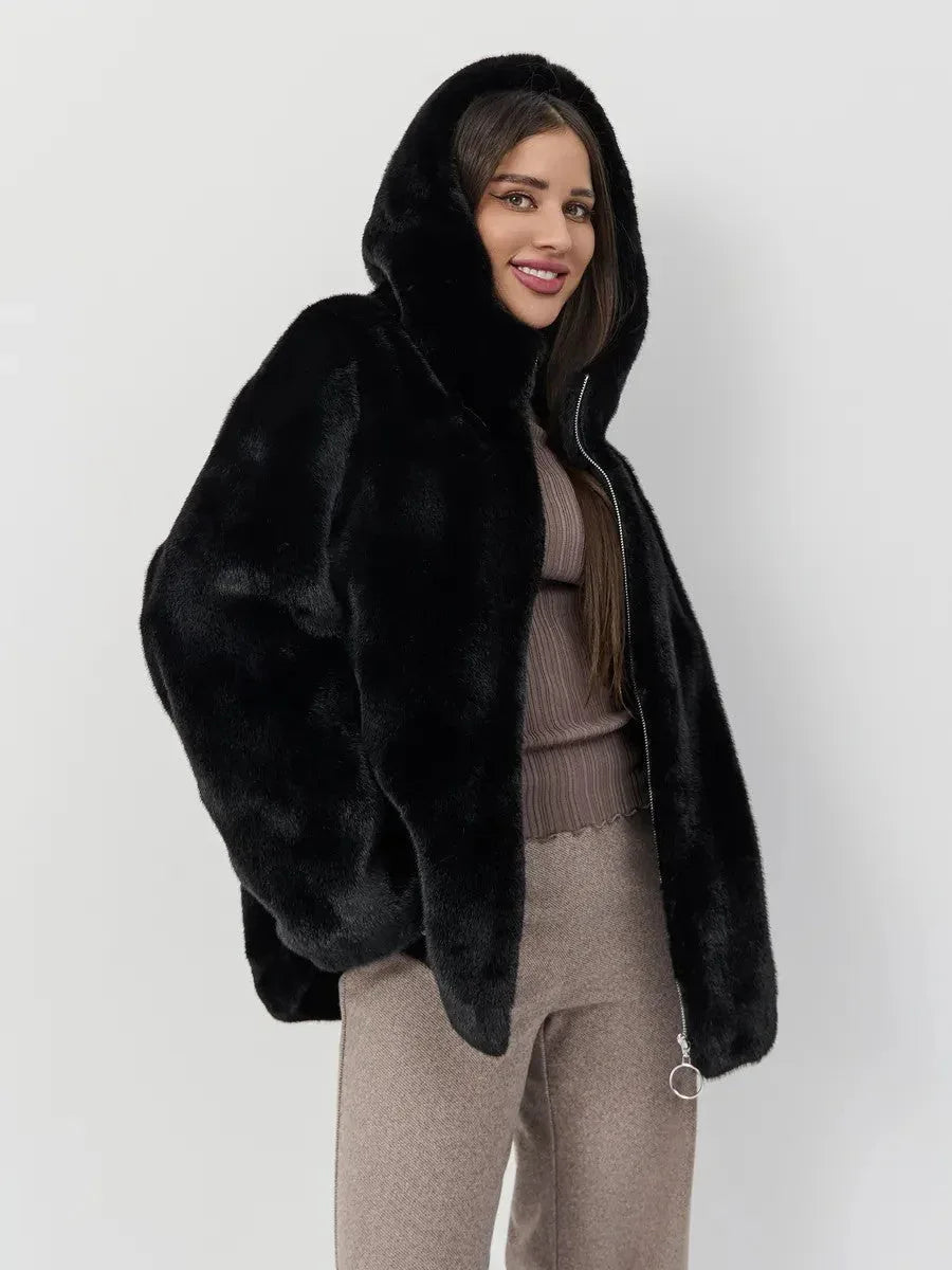 Woman wearing a black hooded faux fur jacket, brown ribbed turtleneck top, and brown wide-leg trousers, smiling and looking forward. Main image