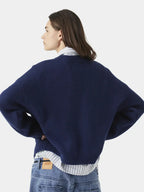 side view of a woman wearing a navy blue crew neck sweater with red "EME STUDIOS" embroidery