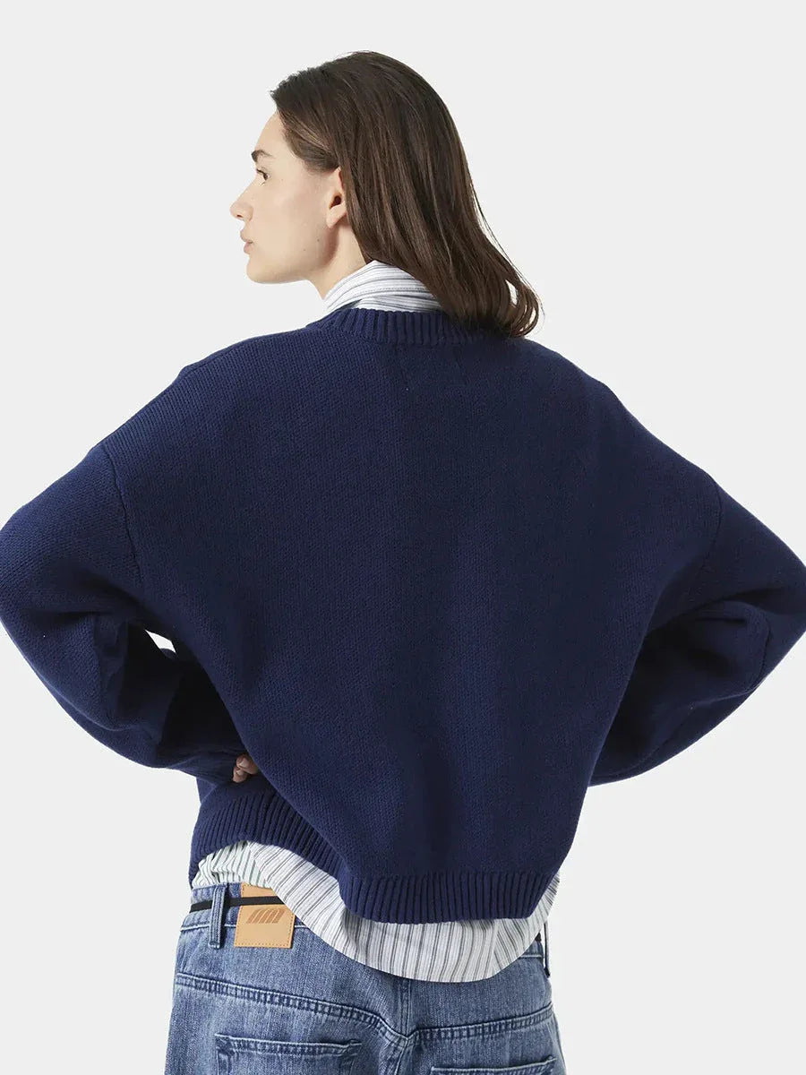 side view of a woman wearing a navy blue crew neck sweater with red "EME STUDIOS" embroidery
