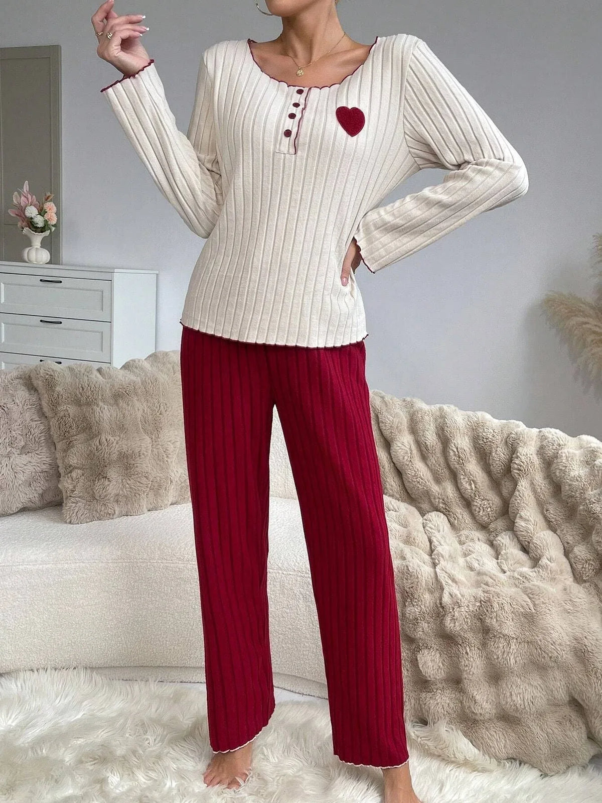 Woman wearing a cream long-sleeve top with red trim and a heart applique, paired with red ribbed pants. Main image