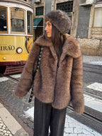 woman wearing a brown faux fur jacket and a fur hat standing near a tram