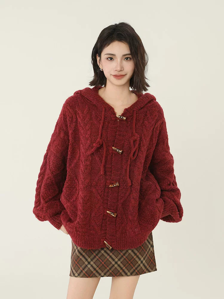 Full view of a woman in a burgundy cable knit hooded cardigan.
