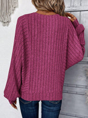 Back view of a woman wearing a magenta ribbed knit sweater with batwing sleeves and blue jeans.