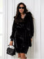 Woman wearing a black hooded faux fur midi coat with a belted waist and zipper details, holding a black handbag.