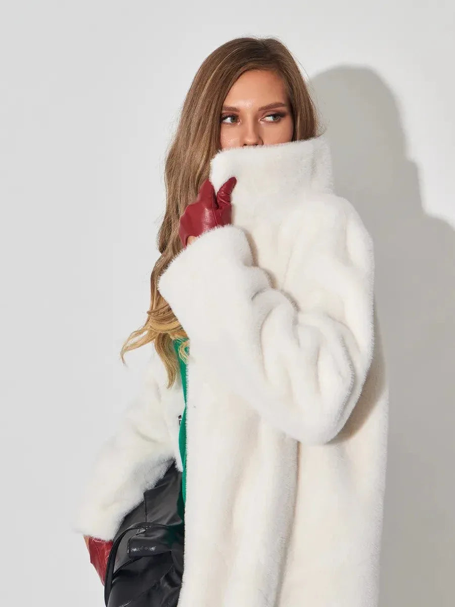 Close-up of a woman wearing a white faux fur coat and red gloves, covering her mouth.