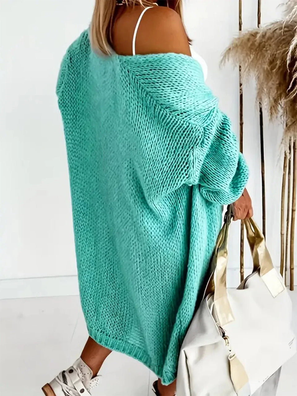 Rear view of a woman wearing a longline aqua knit cardigan, with the cardigan draped off one shoulder. Secondary image