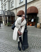 Woman leaning on a lamppost in a white faux fur coat