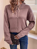 Woman in a mauve knit sweater with a mock neckline and long sleeves, showing the detail of the knot accent.