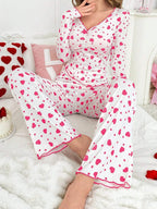 woman wearing white and pink heart print pajama set, seated on bed, facing forward