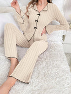 woman sitting on a bed in cream ribbed knit pajama set with black trim