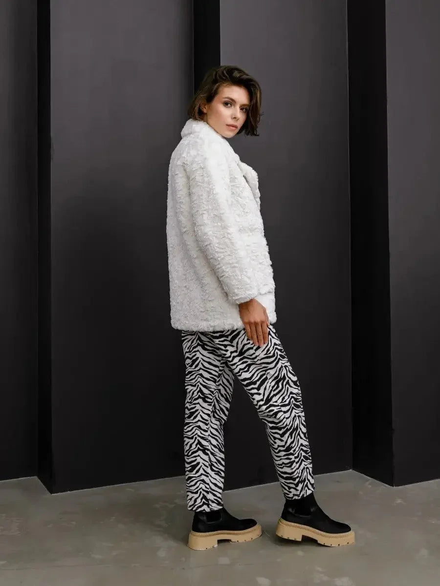 Model posing in a white textured faux fur jacket and zebra print pants.