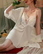 Woman in a white satin slip dress and robe with a rose.