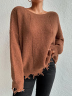 Woman wearing a rust-colored oversized distressed knit sweater with black pants and a necklace