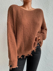 Woman wearing a rust-colored oversized distressed knit sweater with black pants and a necklace