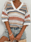 A woman wears a short-sleeved, open-knit striped sweater with a v-neck and denim shorts.
