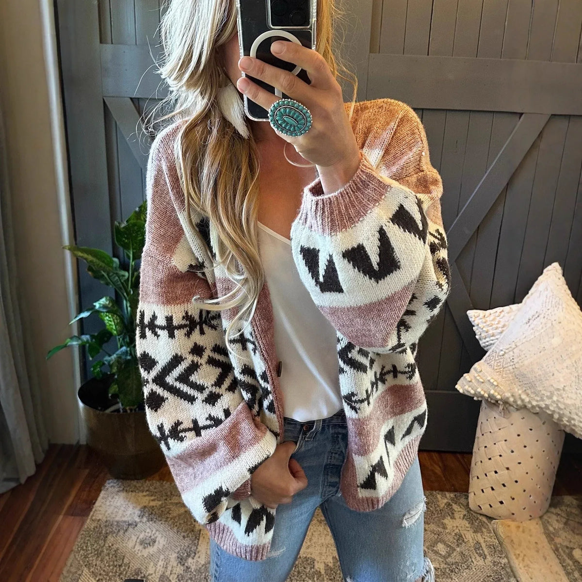 woman wearing a pink and black geometric print knit cardigan with a white tank top and blue jeans