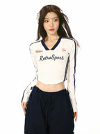 Front view of a woman in a white cropped long-sleeve shirt with contrast trim and 'RetroSport' graphic.