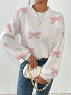 Woman wearing a white crew neck sweater with pink bow print and blue jeans, holding a white clutch purse